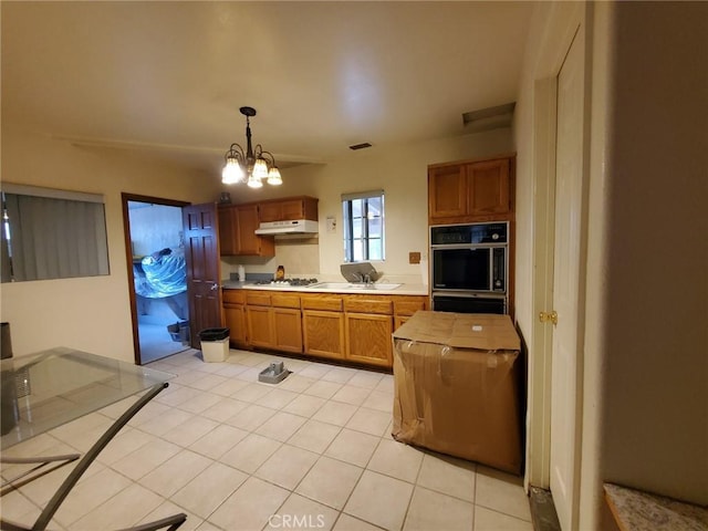 kitchen with white gas cooktop, light tile patterned floors, pendant lighting, and a notable chandelier