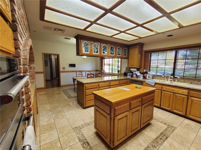 kitchen featuring a fireplace, a kitchen island, light tile patterned floors, and sink