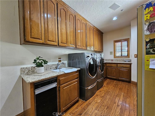 laundry room with washing machine and clothes dryer, hardwood / wood-style floors, a textured ceiling, and sink