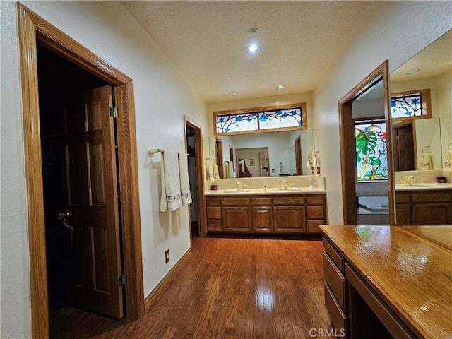 bathroom with hardwood / wood-style floors, vanity, and a textured ceiling