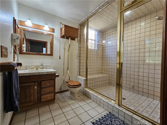 bathroom featuring toilet, vanity, tile patterned floors, and an enclosed shower