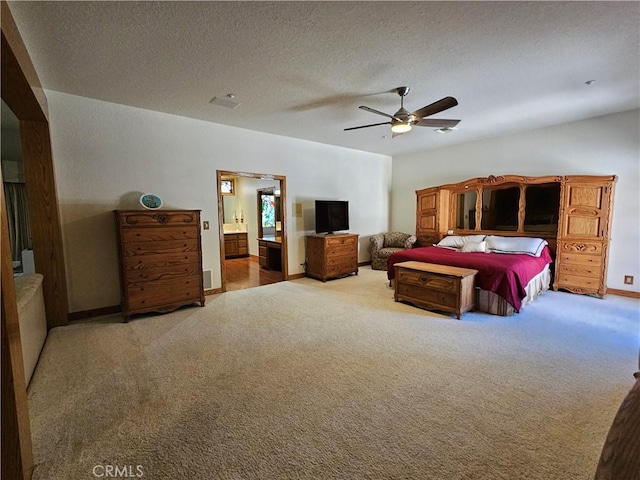 carpeted bedroom with ensuite bathroom, ceiling fan, and a textured ceiling