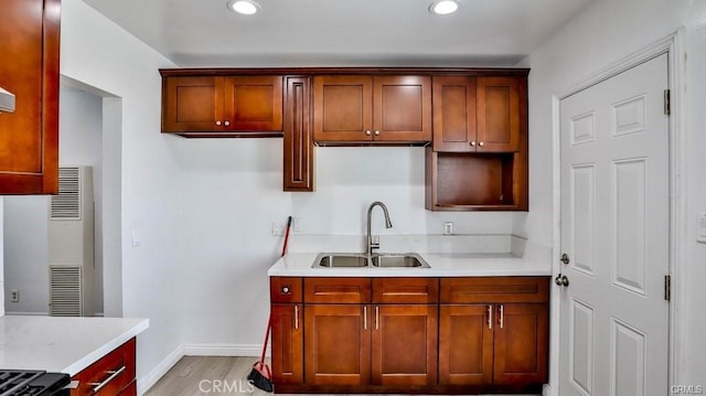 kitchen with light wood-type flooring, sink, and light stone counters