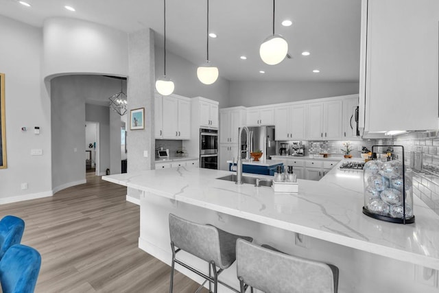 kitchen featuring kitchen peninsula, white cabinetry, pendant lighting, and decorative backsplash