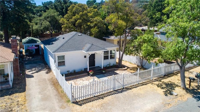 view of front of property with a fenced front yard, a shingled roof, and stucco siding