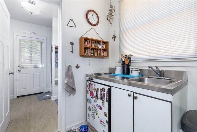 kitchen featuring white cabinetry, light hardwood / wood-style floors, sink, and stainless steel counters