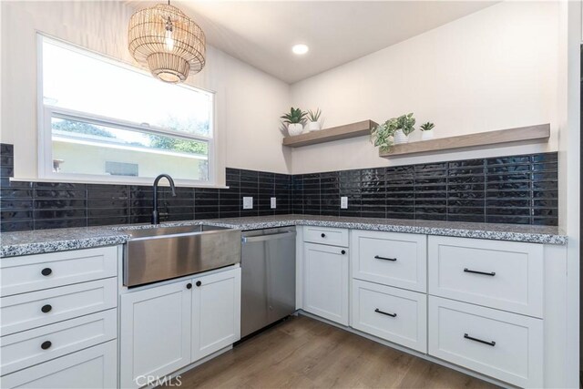 kitchen featuring sink, stainless steel dishwasher, white cabinets, and light stone countertops