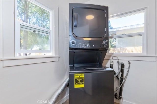 laundry room featuring stacked washing maching and dryer and a healthy amount of sunlight