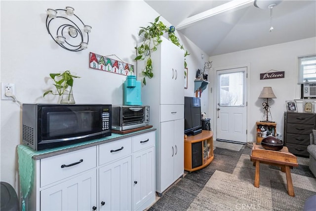 interior space with vaulted ceiling and white cabinets