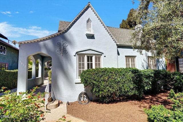 view of side of home featuring stucco siding and roof with shingles