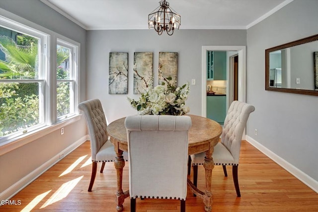 dining room featuring baseboards, an inviting chandelier, light wood-style flooring, and crown molding