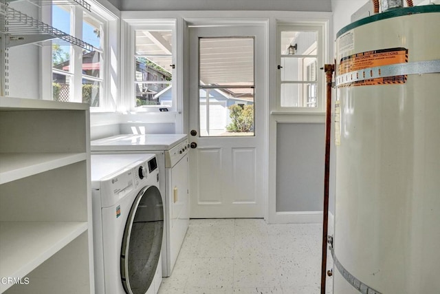 clothes washing area featuring separate washer and dryer, light floors, water heater, and laundry area