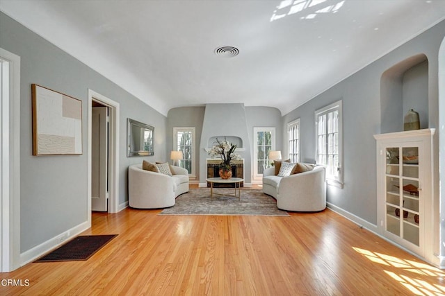 unfurnished living room with visible vents, baseboards, lofted ceiling, and light wood finished floors