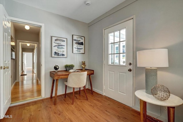 doorway featuring baseboards and light wood-style flooring