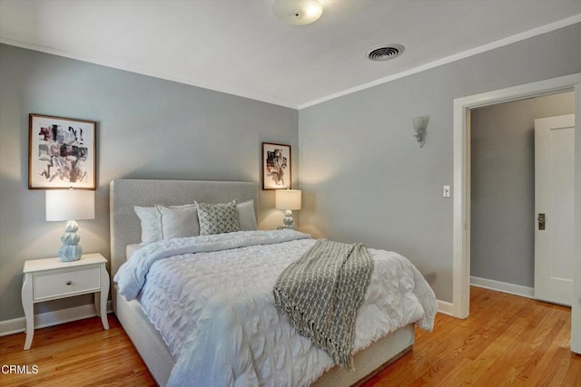 bedroom with visible vents, baseboards, light wood-style floors, and crown molding