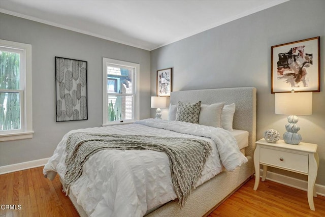 bedroom with crown molding, baseboards, and wood finished floors