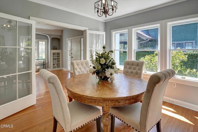 dining space with light wood finished floors, a chandelier, baseboards, and ornamental molding