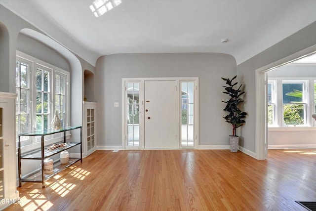 entryway featuring light wood finished floors, visible vents, baseboards, and vaulted ceiling