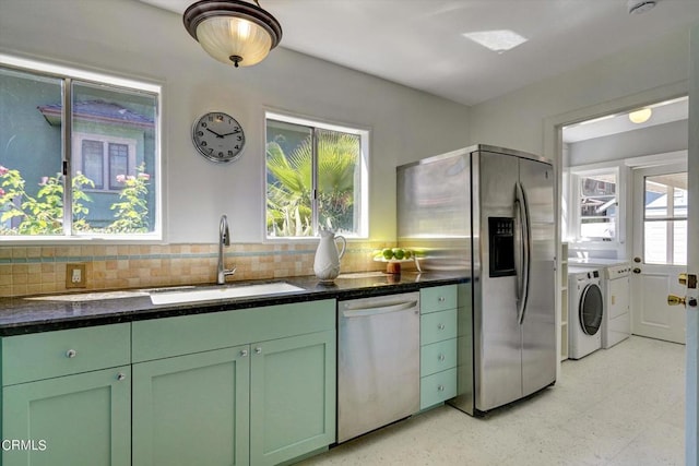 kitchen with green cabinetry, washing machine and dryer, stainless steel appliances, and a sink