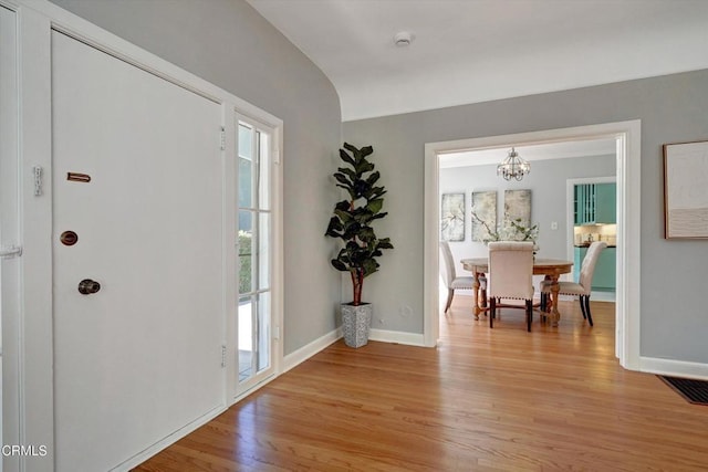 foyer featuring light wood-style floors, visible vents, a chandelier, and baseboards