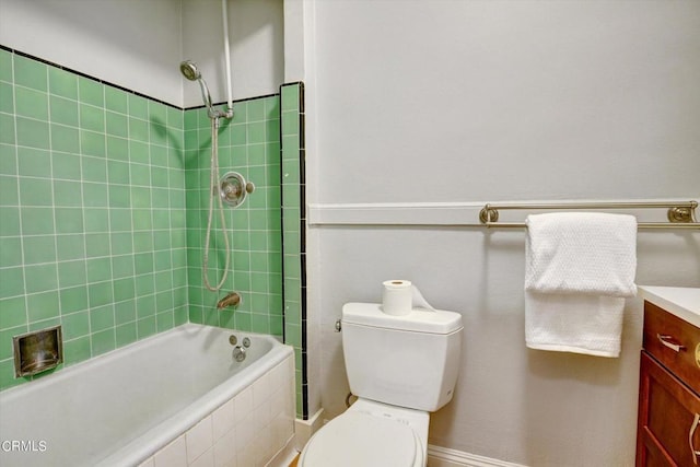 bathroom with toilet, vanity, and tiled shower / bath