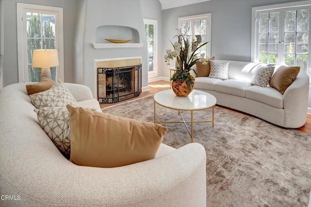 living area with baseboards, wood finished floors, and a tiled fireplace