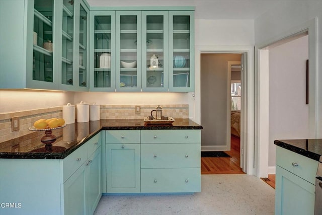 kitchen featuring glass insert cabinets, baseboards, and decorative backsplash