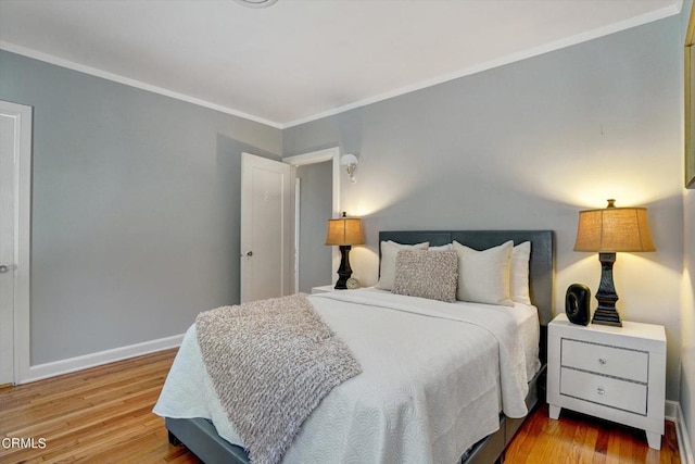 bedroom with wood finished floors, baseboards, and ornamental molding