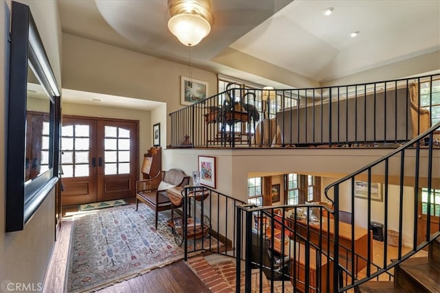 foyer with wood-type flooring, a towering ceiling, and french doors