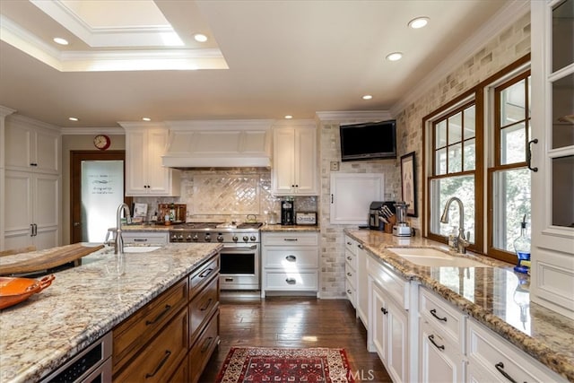 kitchen with white cabinets, high end stainless steel range oven, custom range hood, and sink