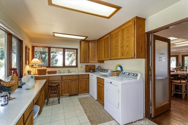 laundry area featuring cabinets, sink, washer and dryer, and a healthy amount of sunlight