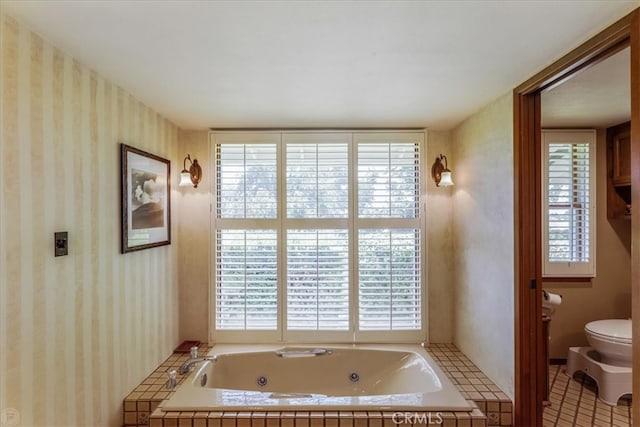 bathroom featuring tiled tub, toilet, and tile patterned flooring