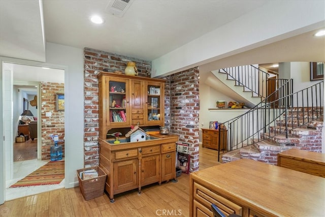 interior space with light hardwood / wood-style flooring and brick wall