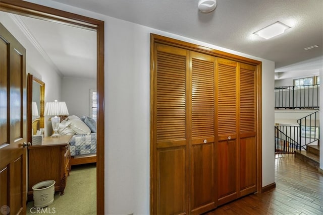 hallway featuring ornamental molding, a textured ceiling, and dark wood-type flooring