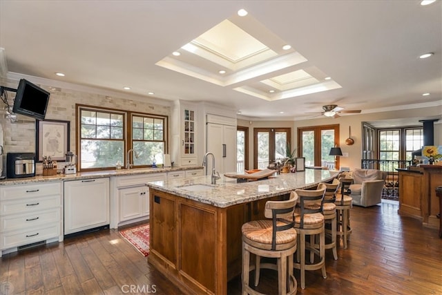 kitchen featuring light stone counters, dark wood-type flooring, a kitchen island with sink, white cabinetry, and ceiling fan