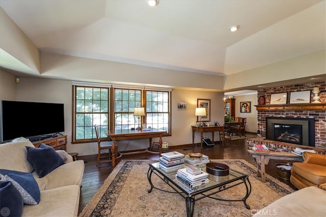 living room with a fireplace, vaulted ceiling, and dark hardwood / wood-style floors