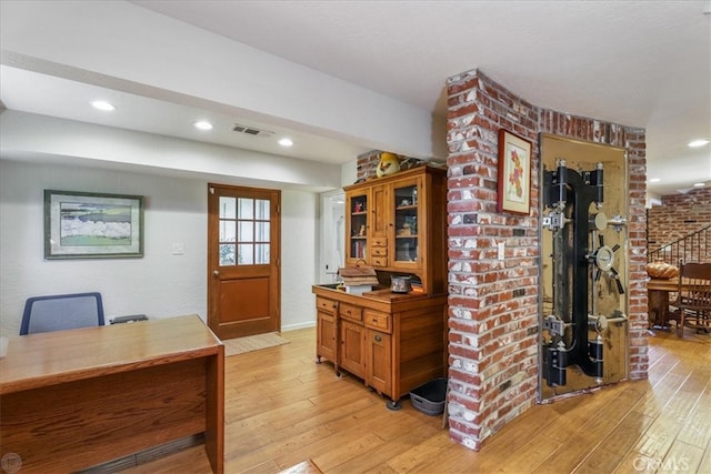 office area with light hardwood / wood-style floors and brick wall