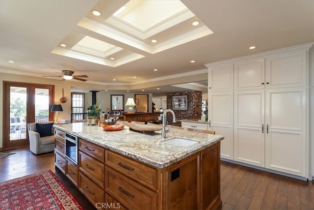 kitchen featuring dark hardwood / wood-style flooring, white cabinetry, a center island with sink, and sink