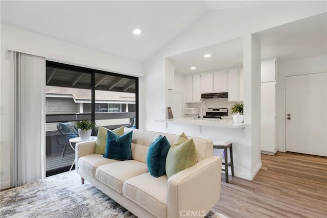 living area with vaulted ceiling, baseboards, light wood-style flooring, and recessed lighting