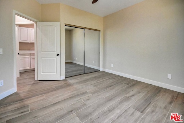 unfurnished bedroom with ceiling fan, a closet, and light hardwood / wood-style floors