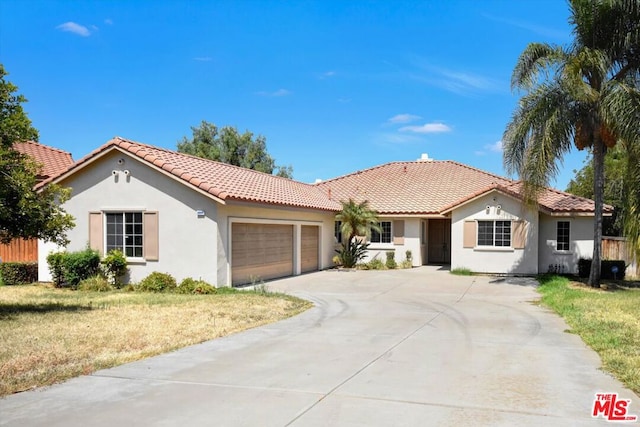 mediterranean / spanish-style house with a garage and a front lawn