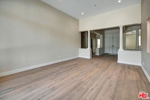 unfurnished room with light wood-type flooring and ornate columns