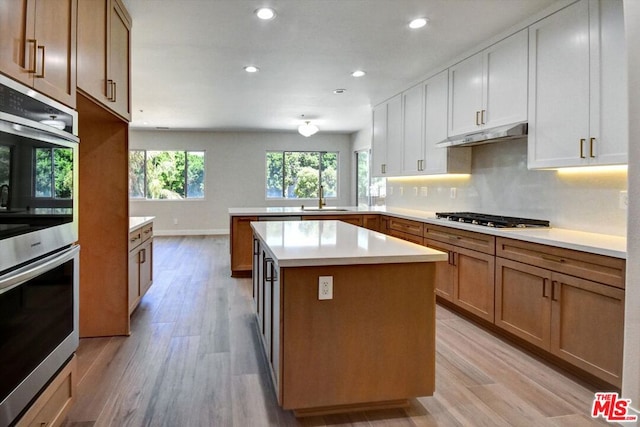 kitchen featuring sink, kitchen peninsula, light hardwood / wood-style flooring, white cabinetry, and appliances with stainless steel finishes