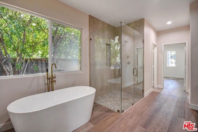 bathroom with hardwood / wood-style flooring and independent shower and bath