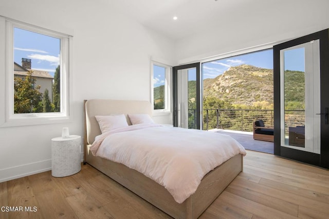 bedroom featuring access to exterior, a mountain view, and light hardwood / wood-style flooring