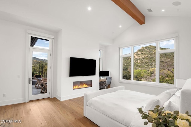 bedroom featuring access to exterior, beam ceiling, light wood-type flooring, and multiple windows