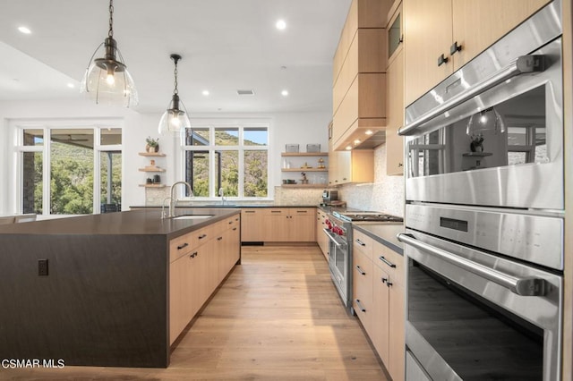 kitchen featuring light brown cabinetry, appliances with stainless steel finishes, sink, decorative light fixtures, and light hardwood / wood-style floors