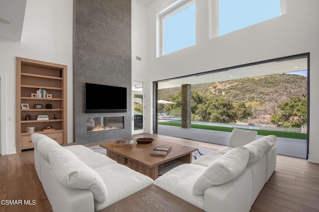 living room featuring a fireplace, wood-type flooring, and a high ceiling