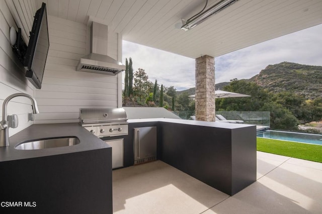 view of patio featuring an outdoor kitchen, area for grilling, a mountain view, and sink