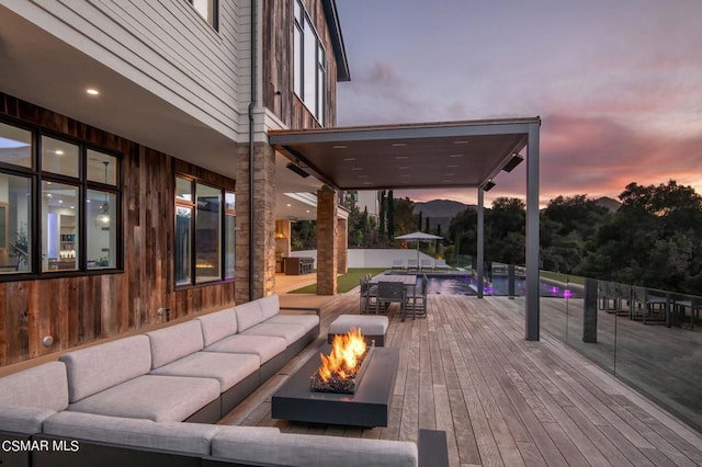 patio terrace at dusk featuring an outdoor living space with a fire pit and a deck